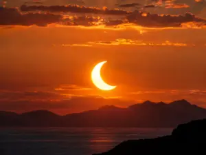 Fotografia realistica di un'eclissi solare parziale al tramonto con cielo dai toni caldi.
