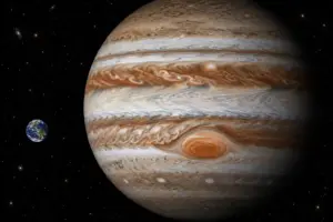 Confronto dimensionale realistico tra il pianeta Giove e la Terra nello spazio profondo.